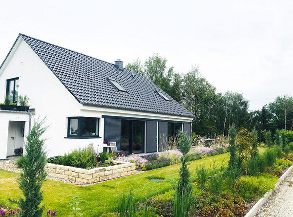 Schiebeläden in anthrazit vor den Terrassentüren eines weißen Hauses