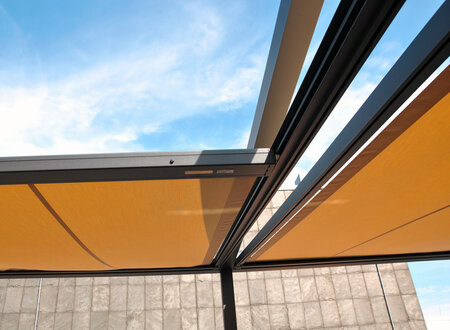 Q.Bus System mit antrazitfarbendem Metallgestell und verfahrbaren Stofftüchern in beigebraun auf einer Dachterrasse