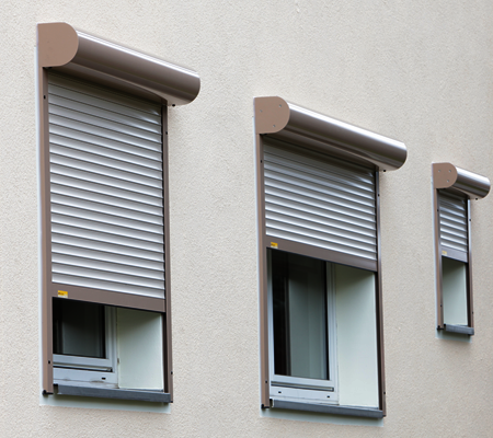 Referenz Rollläden: Detailansicht Fensterfront mit nachträglich angebauten alufarbenden Rollläden, teilweise heruntergefahren.