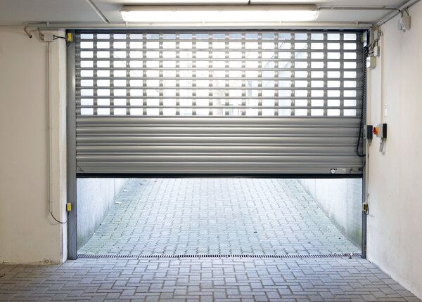 Halboffenes graues Rolltor einer Tiefgarageneinfahrt
