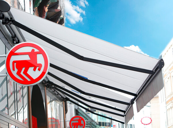 Ladenmarkise in weiß mit antrazitfarbenden Metallstützen als Sonnenschutz für den Laden und die Aussenware
