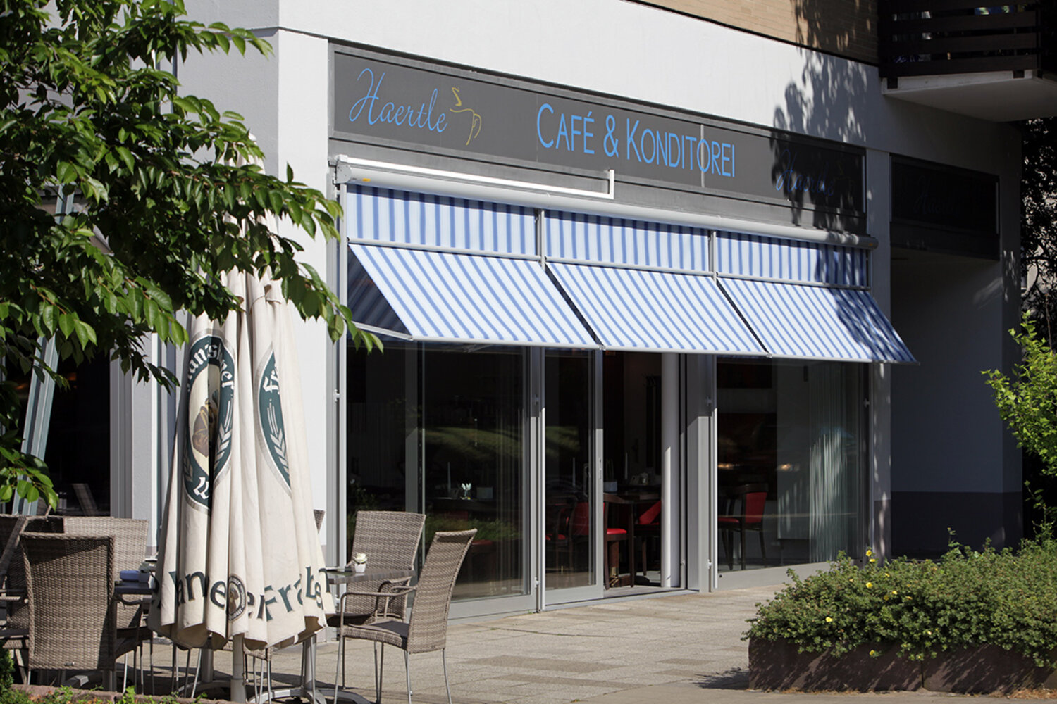 Ausgefahrende Markisoletten, blau-weiß gestreift, an der Fensterfront eines Cafés Ausgefahrende Markisoletten, blau-weiß gestreift, an der Fensterfront eines Cafés