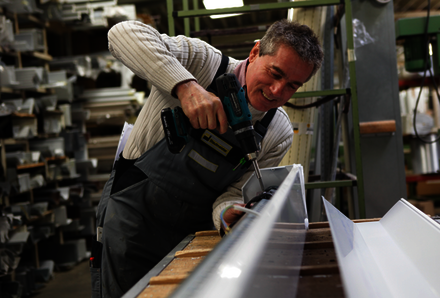 Ein Mitarbeiter in der hauseigenen Stautmeister Werkstatt bei der Montage eines Rollladenkastens