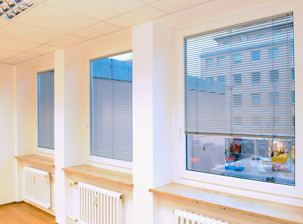 Ausblick durch drei Fenster eines Raumes mit heruntergelassenen Innenjalousien in weiß