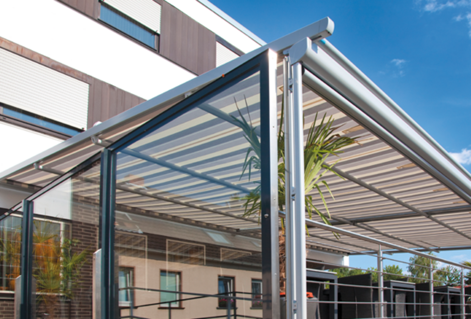 Detailansicht eines Wintergartens mit Unterglasmarkise unter dem Dach und klappbaren Glas-Seitenelementen Detailansicht eines Wintergartens mit Unterglasmarkise unter dem Dach und klappbaren Glas-Seitenelementen